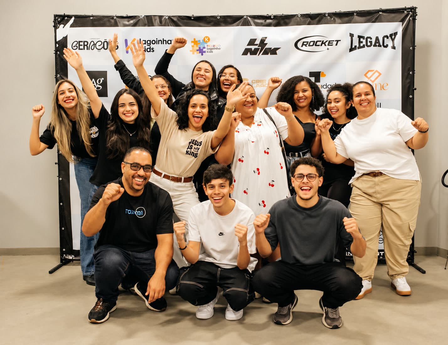 Grupo de alunos e líderes comemorando juntos, de braços levantados