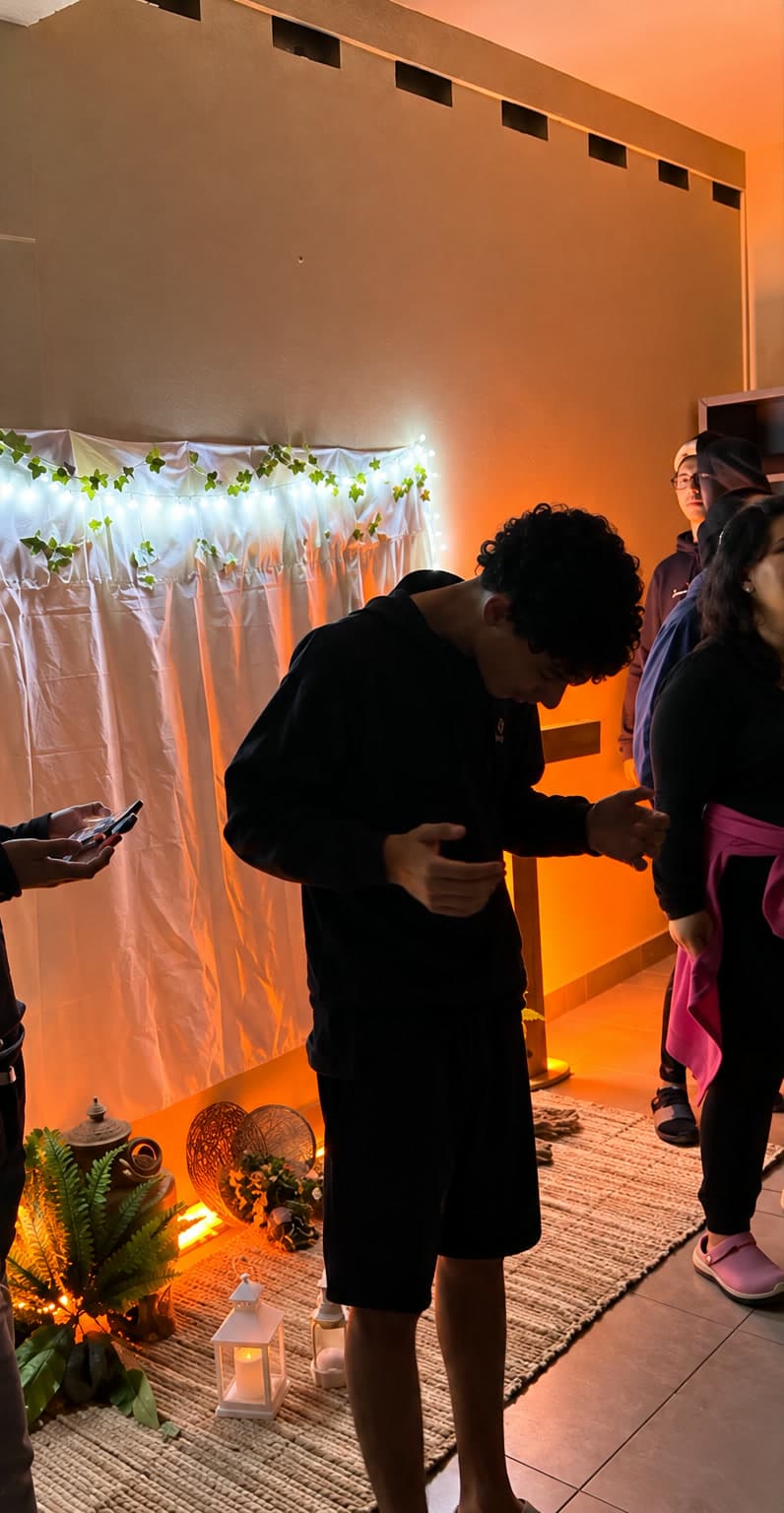 Jovem em oração numa sala preparada com luzes, cortina branca e velas